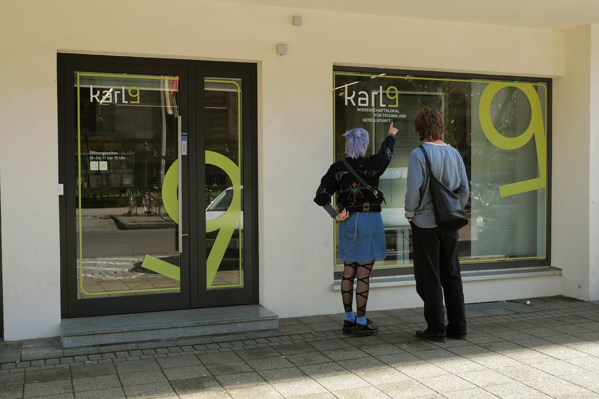 Two people looking through the window of Karl9.